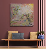 Load image into Gallery viewer, An abstract floral canvas painting in a square format, displayed on a dusty rose wall above a wooden bench with decorative pillows and a plant.
