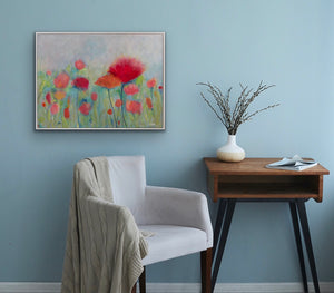 Gentle and serene poppies in a field shown above a chair on a pale blue wall.