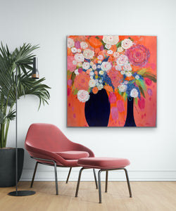 Shown in a room setting of white wall and rose coloured chair and ottoman