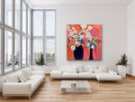 Load image into Gallery viewer, Two black vases with orange, pink, and white flowers on a white wall above a white sofa.
